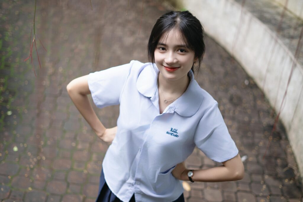 Smiling young woman in a school uniform outdoors, conveying positivity and youthful energy.